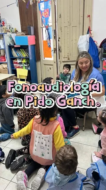 Una mujer sentada lee a un grupo de niños en el piso de la sala